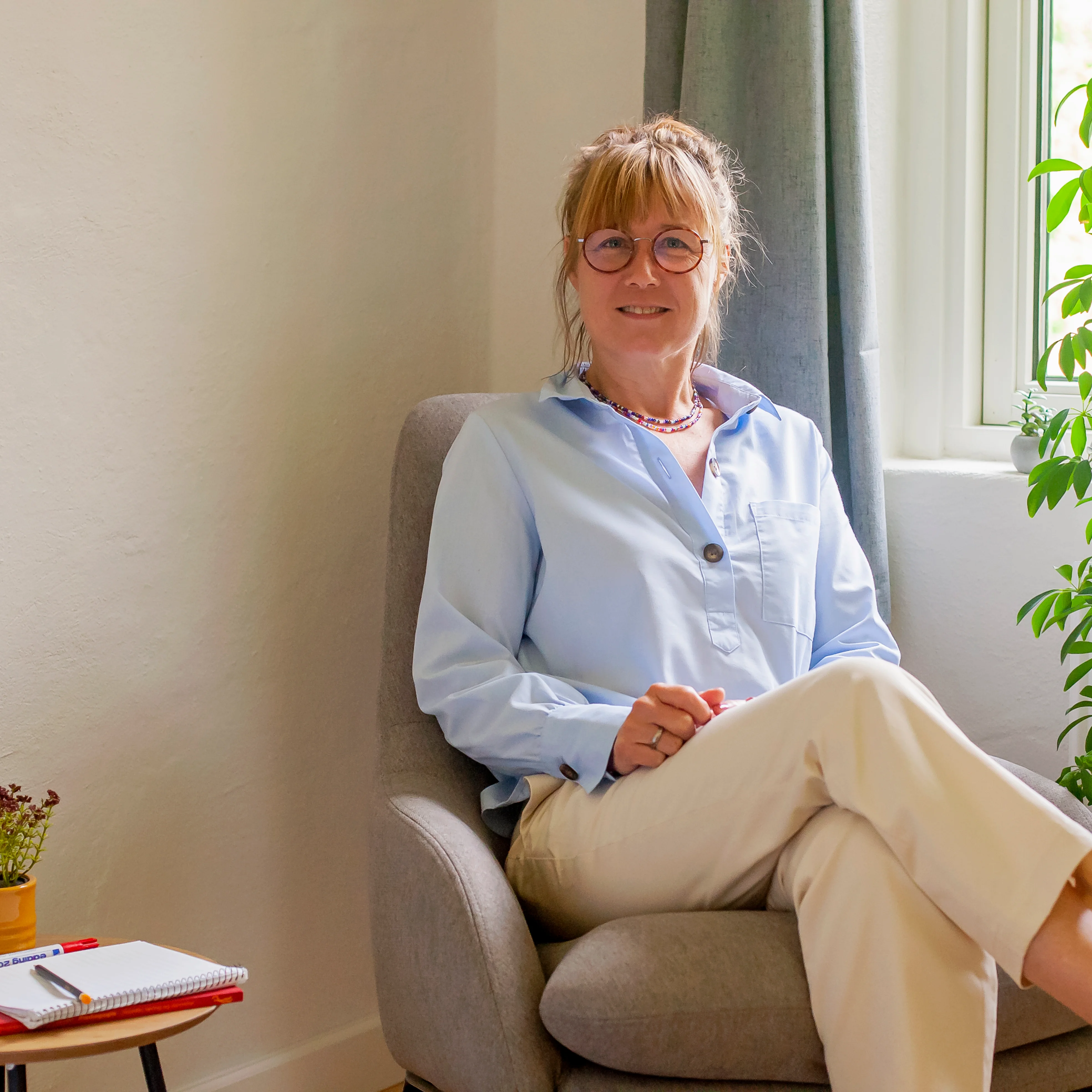 Therapist sitting in grey chair in cozy home office
